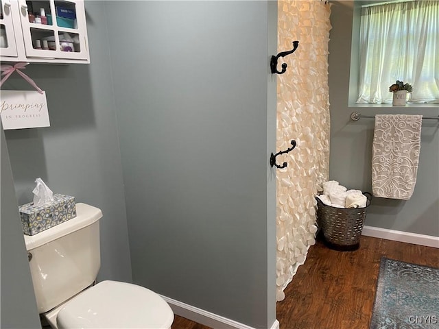 full bathroom featuring toilet, wood finished floors, and baseboards