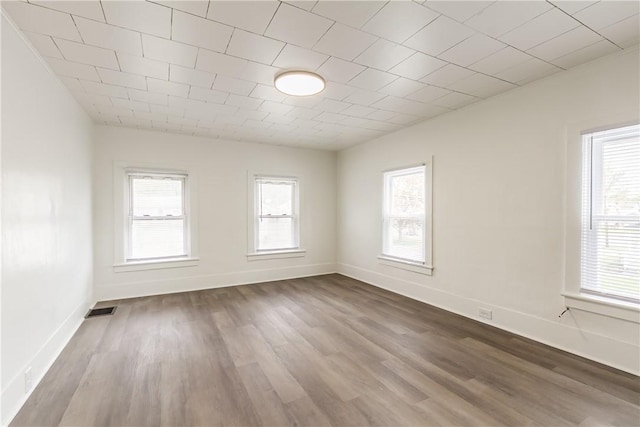 unfurnished room featuring baseboards, a healthy amount of sunlight, and dark wood-style floors