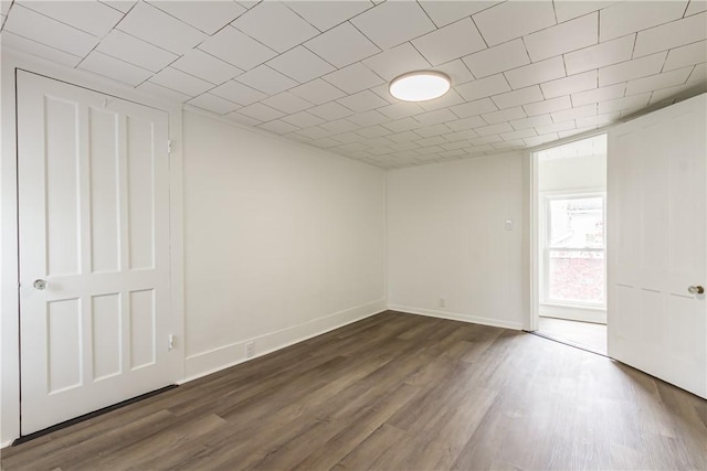 unfurnished room with baseboards and dark wood-style floors