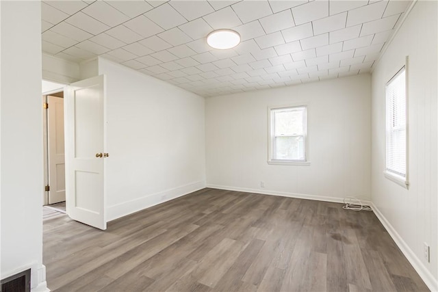 spare room with baseboards, visible vents, and wood finished floors