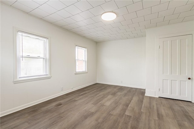spare room featuring baseboards and dark wood-style floors