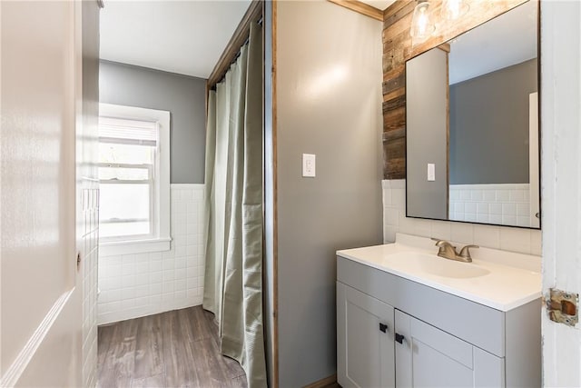 full bath featuring a shower with curtain, tile walls, vanity, and wood finished floors