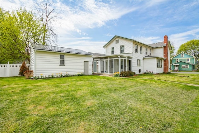 rear view of house with a yard, a sunroom, and fence