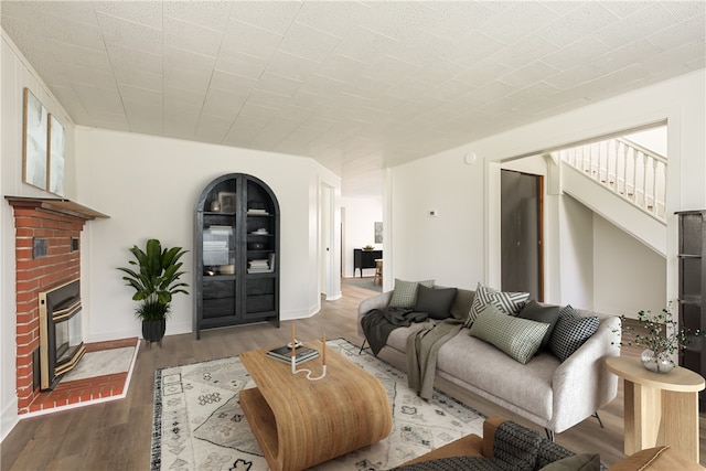 living area with baseboards, wood finished floors, and a fireplace