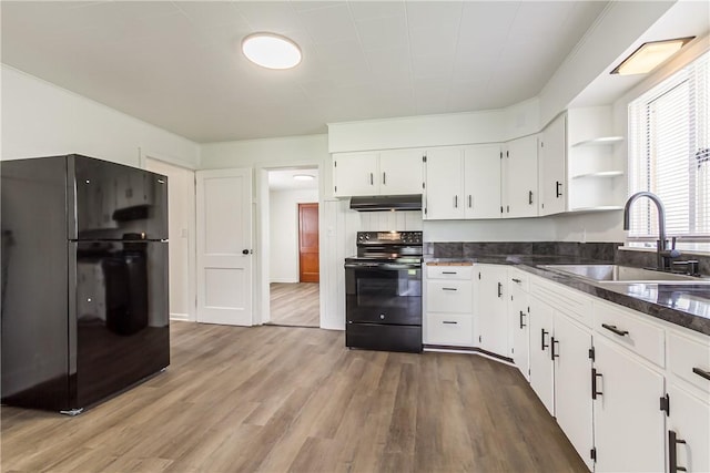 kitchen featuring wood finished floors, a sink, range hood, white cabinets, and black appliances