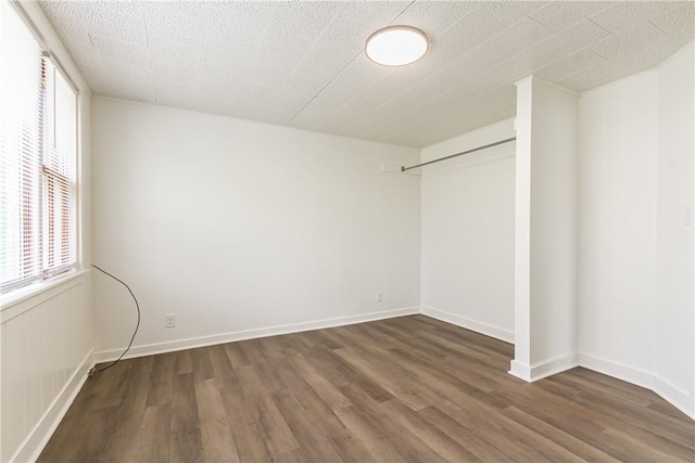 spare room with baseboards, plenty of natural light, and wood finished floors