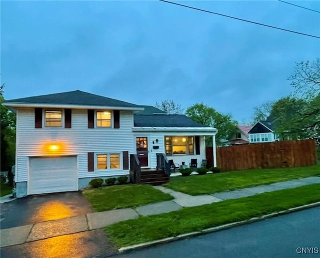 tri-level home featuring driveway, a garage, fence, and a front yard