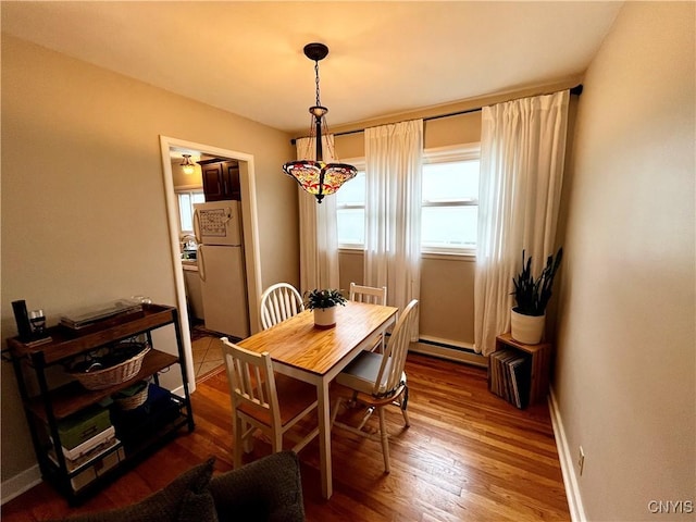 dining space featuring baseboards, baseboard heating, and wood finished floors