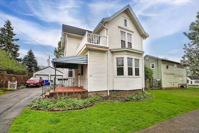 traditional-style house with a detached garage, a front yard, and a balcony