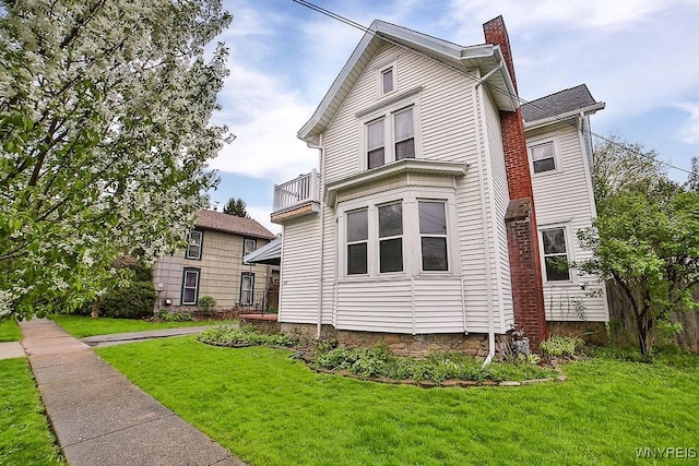 view of front of property with a front lawn, a chimney, and a balcony