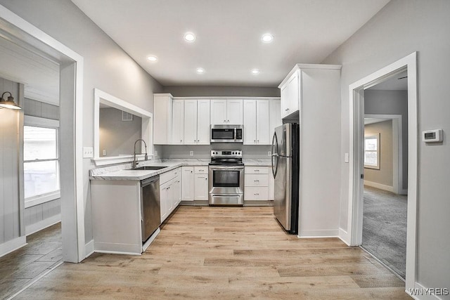 kitchen with baseboards, a sink, white cabinetry, light countertops, and appliances with stainless steel finishes