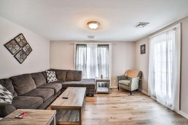 living area with plenty of natural light, baseboards, visible vents, and light wood-style floors