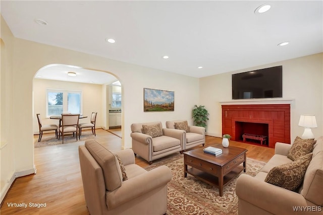 321 Eggert Rd, Cheektowaga, NY 14215 - living room with arched walkways, light wood-type flooring, recessed lighting, a brick fireplace, and baseboards