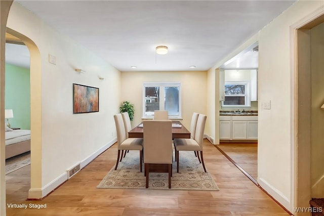 321 Eggert Rd, Cheektowaga, NY 14215 - dining space featuring light wood-style flooring, baseboards, and arched walkways