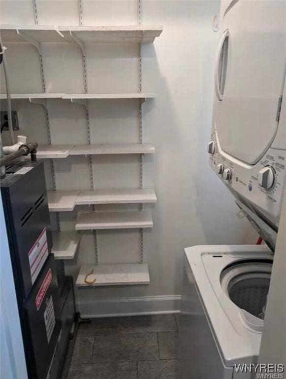 laundry area with baseboards, laundry area, and stacked washer / drying machine