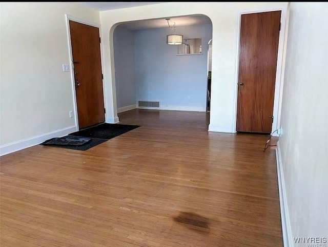 interior space with visible vents, wood finished floors, baseboards, and arched walkways