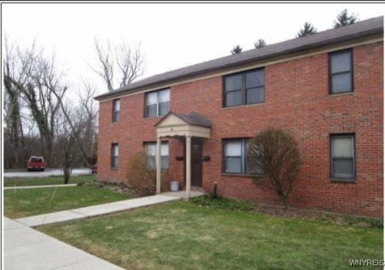 colonial house with a front lawn and brick siding