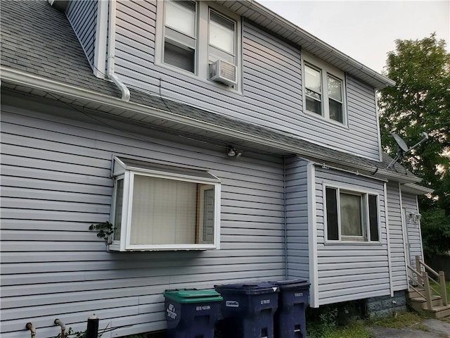 view of side of home with roof with shingles