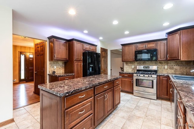kitchen featuring black appliances, backsplash, a kitchen island, a sink, and light tile patterned flooring