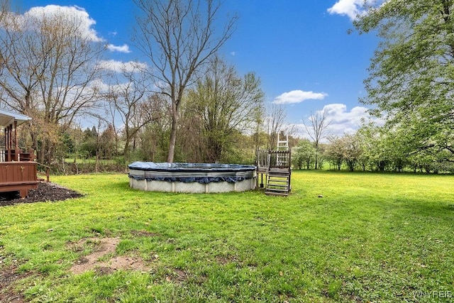 view of green lawn featuring stairway, a covered pool, and a deck