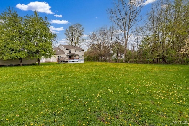 view of green lawn featuring a wooden deck