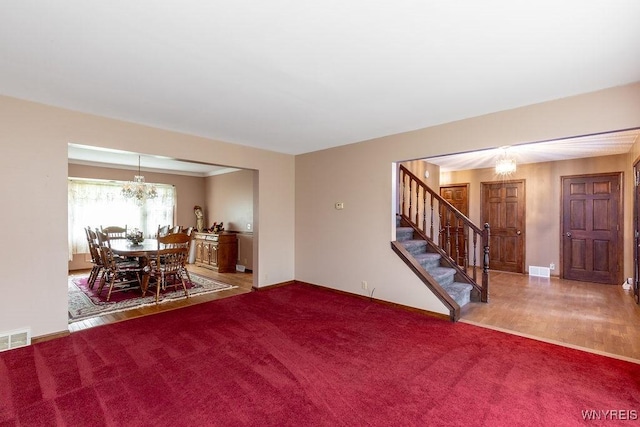 living area with a chandelier, carpet flooring, stairs, and baseboards