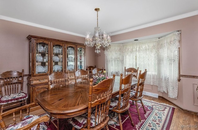 dining area featuring a chandelier, crown molding, light wood-style flooring, and baseboards
