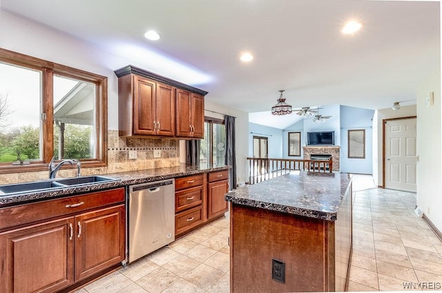 kitchen featuring dishwasher, a sink, a fireplace, tasteful backsplash, and lofted ceiling