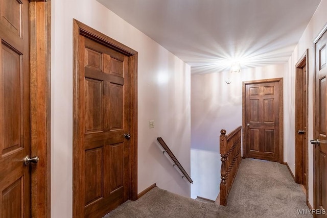 corridor featuring an upstairs landing, carpet floors, and baseboards