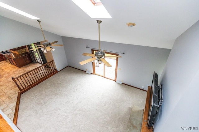 unfurnished living room featuring vaulted ceiling, a ceiling fan, a skylight, baseboards, and carpet floors