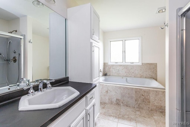 bathroom with vanity, a garden tub, and a shower