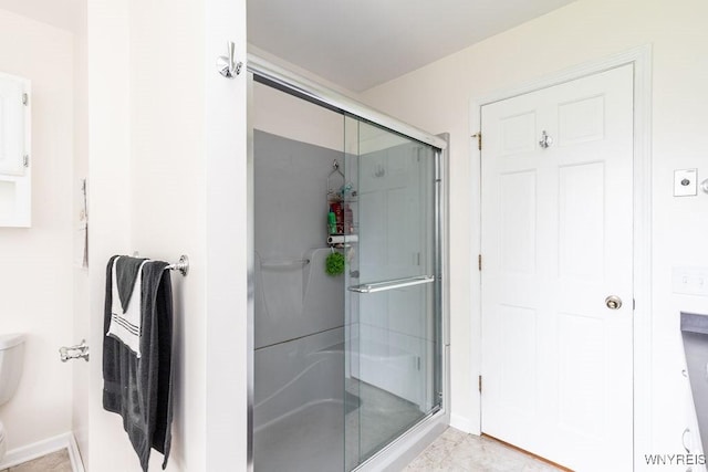 full bathroom featuring a shower stall, toilet, and baseboards