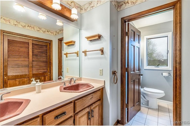 bathroom featuring tile patterned flooring, toilet, baseboards, and double vanity