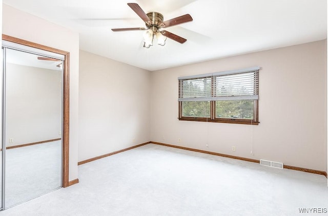 empty room with light carpet, ceiling fan, and baseboards