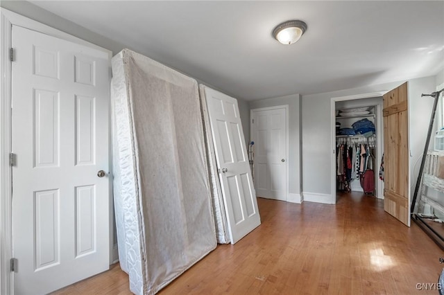 corridor featuring light wood-style flooring and baseboards
