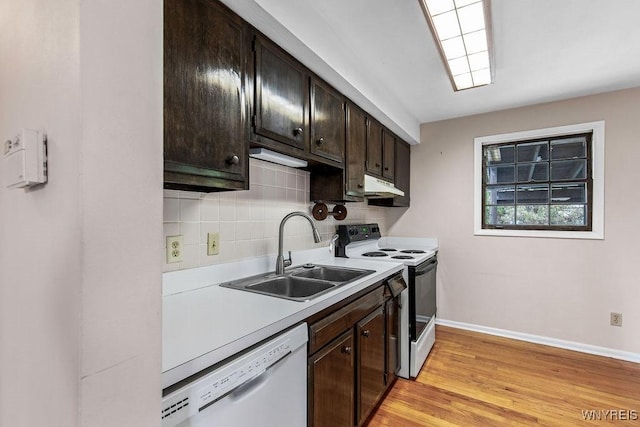 kitchen with a sink, under cabinet range hood, white dishwasher, baseboards, and range with electric cooktop