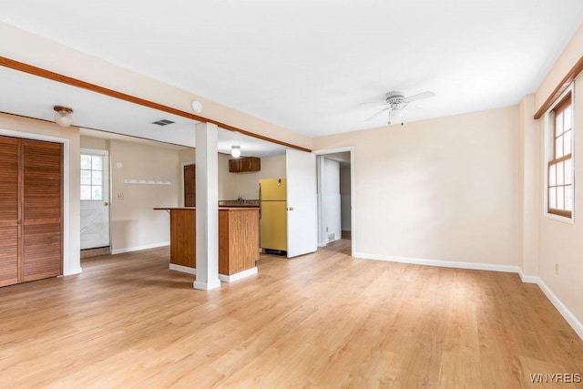 unfurnished living room featuring visible vents, light wood-style flooring, baseboards, and ceiling fan