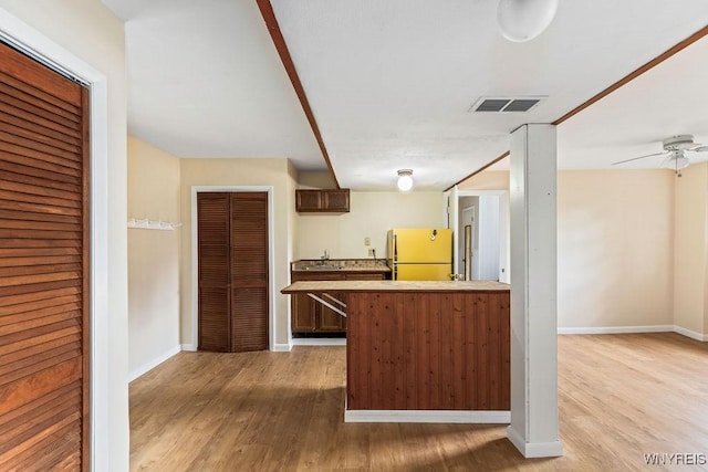 kitchen with a sink, freestanding refrigerator, visible vents, light wood-style flooring, and baseboards