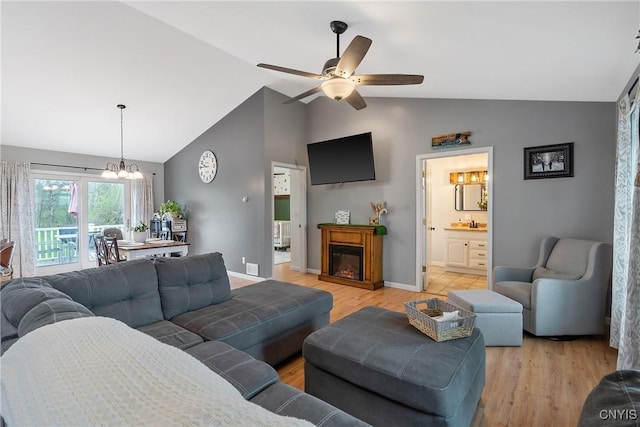 26519 State Route 180, Brownville, NY 13634 - living area with ceiling fan with notable chandelier, high vaulted ceiling, light wood-type flooring, baseboards, and a glass covered fireplace
