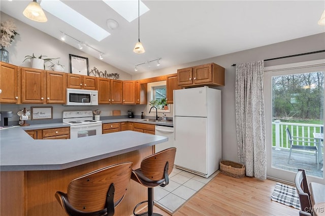 26519 State Route 180, Brownville, NY 13634 - kitchen featuring a peninsula, a sink, vaulted ceiling with skylight, track lighting, and white appliances