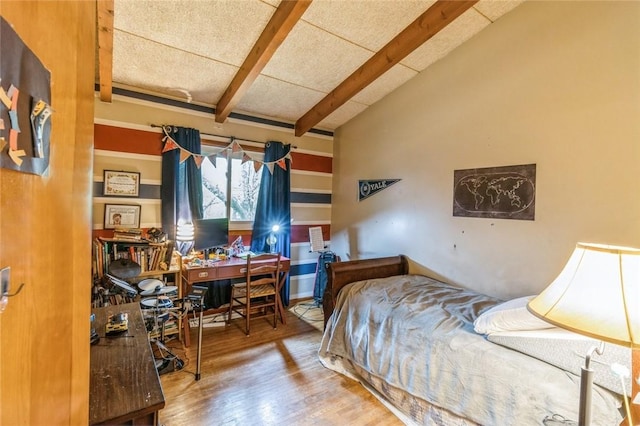 bedroom with lofted ceiling with beams and wood finished floors
