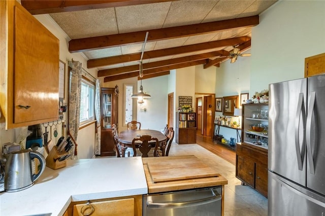 kitchen featuring a ceiling fan, freestanding refrigerator, brown cabinetry, vaulted ceiling with beams, and decorative light fixtures