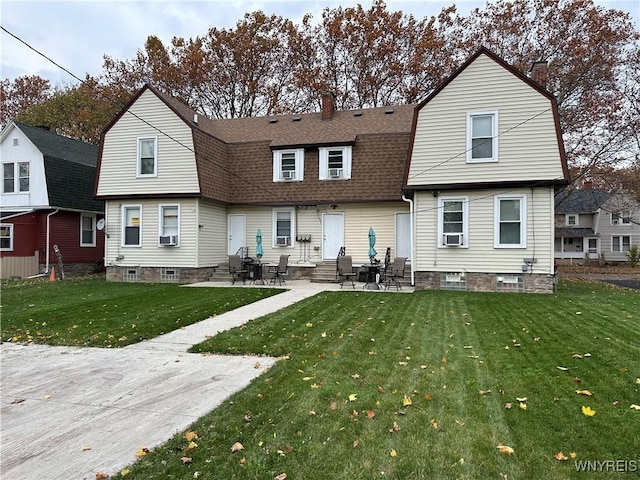 back of property featuring a yard, entry steps, a shingled roof, and a gambrel roof