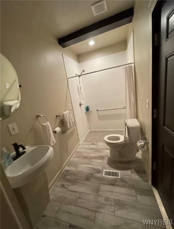 full bathroom featuring toilet, a shower with curtain, visible vents, and a sink