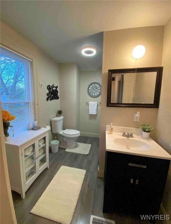 bathroom featuring toilet, baseboards, vanity, and wood finished floors