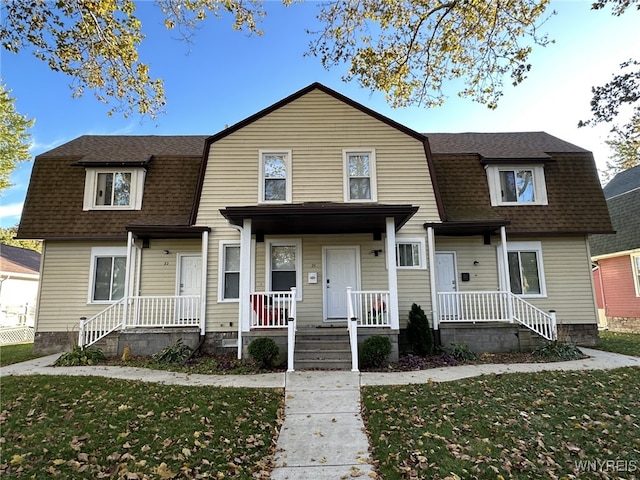 colonial inspired home with a front lawn, a gambrel roof, and a shingled roof