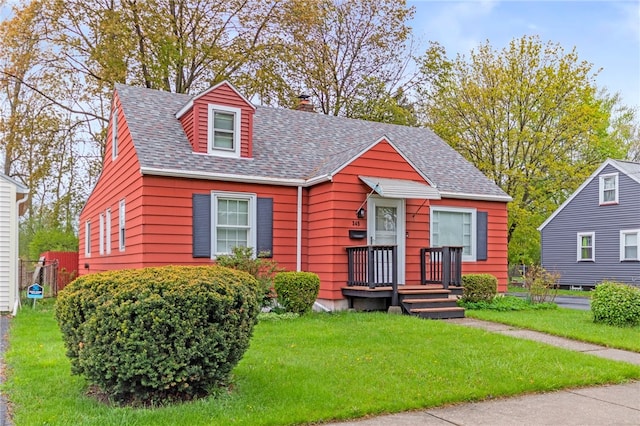 view of front of home featuring roof with shingles, a chimney, and a front yard