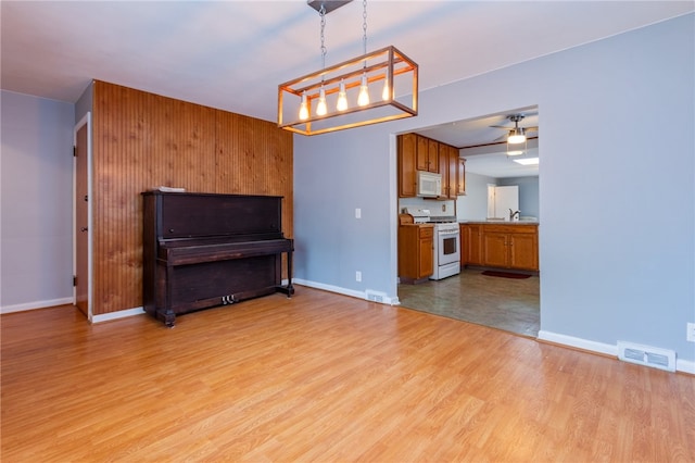 unfurnished living room with light wood-type flooring, visible vents, baseboards, and ceiling fan