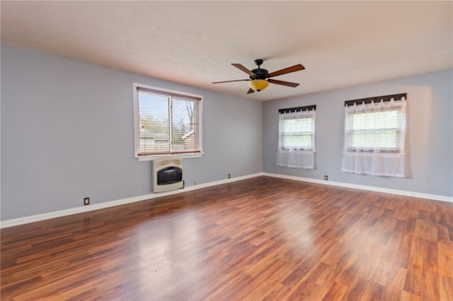 empty room with a wealth of natural light, baseboards, a ceiling fan, and wood finished floors