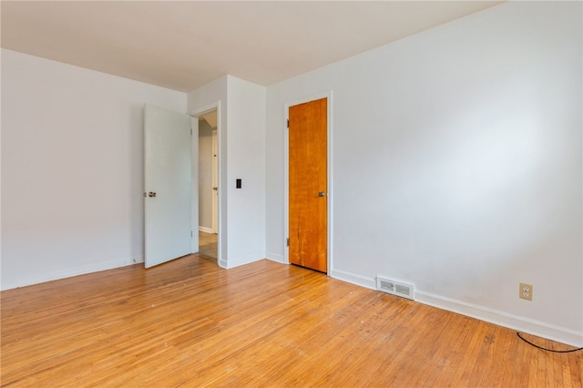 spare room with light wood finished floors, baseboards, and visible vents